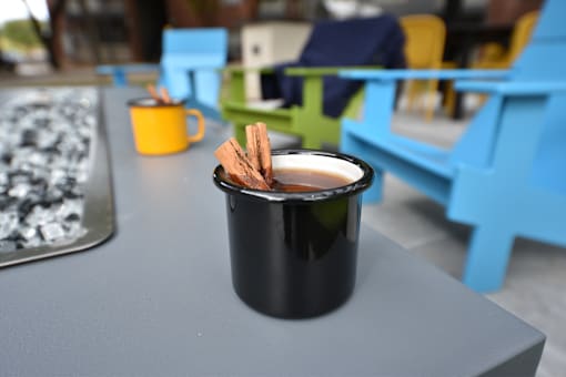 A black mug with cinnamon sticks on a grey table.