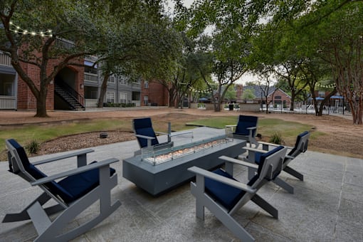 A fire pit surrounded by chairs in a courtyard.