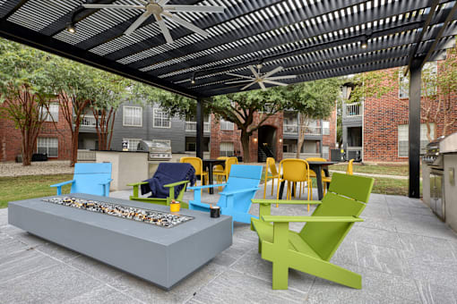 A patio with a fire pit and chairs.