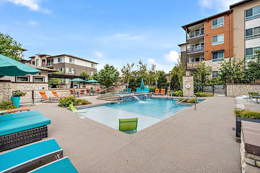 A swimming pool surrounded by a patio with chairs and umbrellas.