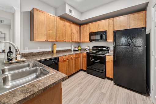 A kitchen with black appliances and wooden cabinets.