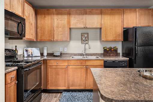 A kitchen with wooden cabinets and black appliances.