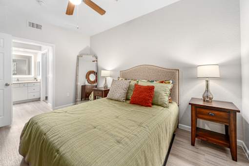 A bedroom with a bed, nightstand, and a ceiling fan.