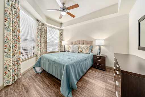 A bedroom with a bed, nightstand, and a ceiling fan.