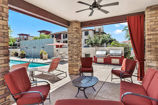 A patio with red chairs and a table.