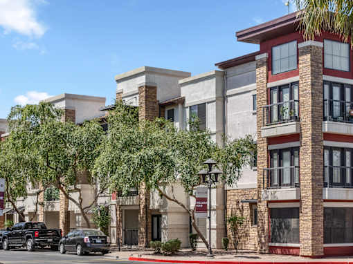 A street view of a multi-story building with a parking lot in front.