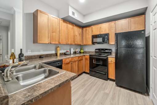 A kitchen with black appliances and wooden cabinets.