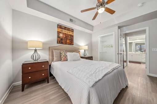 A bedroom with a large bed, a wooden dresser, and a ceiling fan.