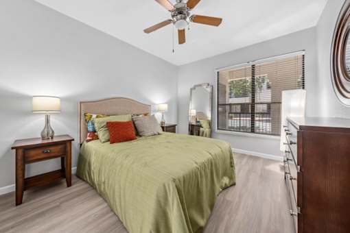 A bedroom with a bed, nightstand, and a ceiling fan.