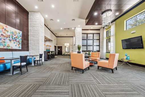 A modern office lounge with a variety of seating options and a colorful mural on the wall.