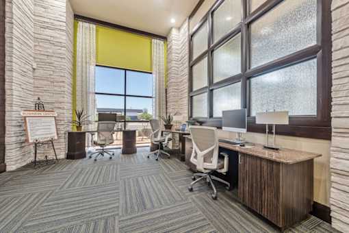 A room with a carpeted floor and a wooden desk with a computer on it.
