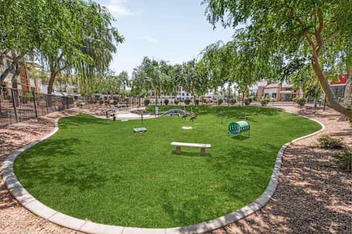 A park with a green lawn and a bench.