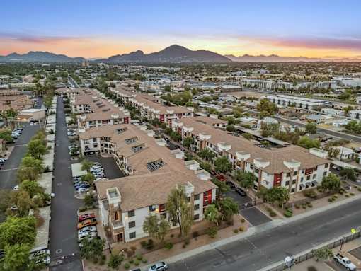 A sunset view of a residential area with apartment buildings and cars parked in the driveways.