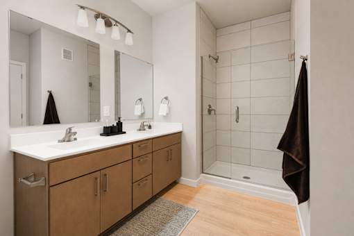 A bathroom with a double sink vanity and a walk in shower.