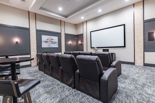 a large screening room with leather chairs and a projector screen