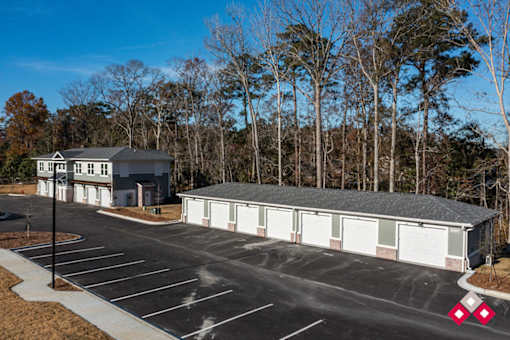 A parking lot with a building and trees in the background.