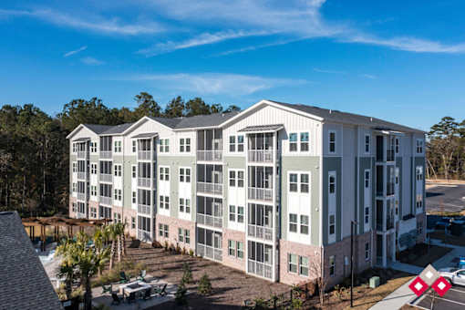 A large apartment complex with multiple buildings and a parking lot in front.