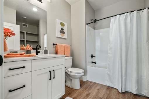 A white bathroom with a toilet, sink, and shower.