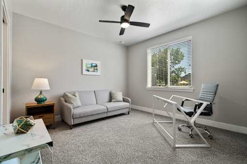 A living room with a grey couch, a white chair, and a green lamp.