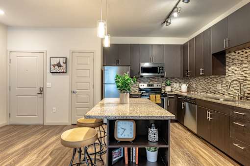 A kitchen with a granite countertop and wooden floors.