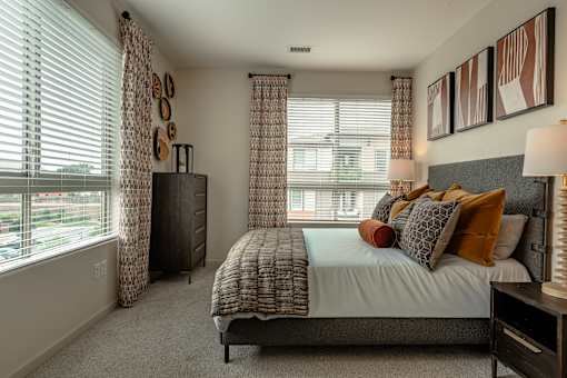 A bedroom with a bed, nightstand, and window with curtains.