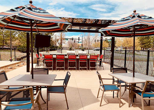 A patio with tables and chairs under striped umbrellas.
