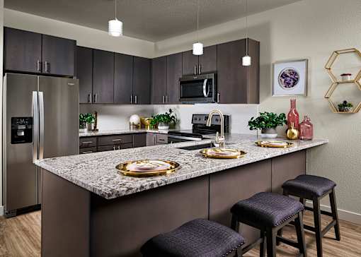 A modern kitchen with a granite countertop and dark brown cabinets.
