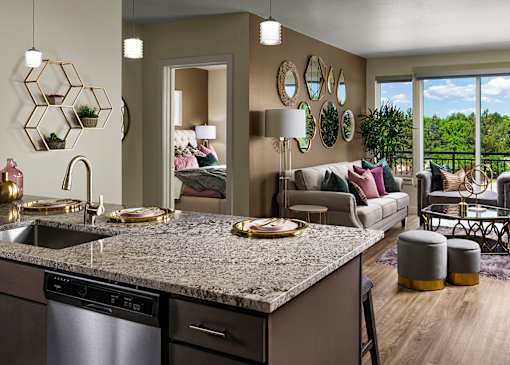 A modern kitchen with a granite countertop and a dining area with a couch and chairs.