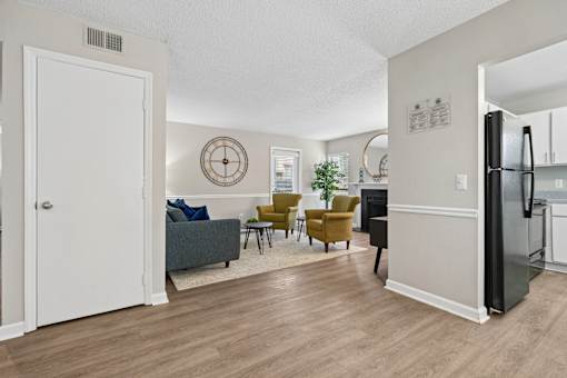 A living room with a couch, chairs, and a refrigerator.