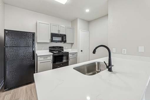 A kitchen with a black refrigerator, stove, and oven.