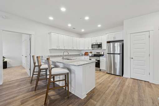A kitchen with white cabinets and a wooden floor.