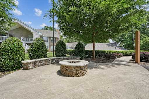 A stone fire pit sits in the middle of a concrete patio.