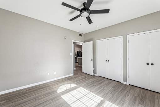 A room with a ceiling fan and three white doors.