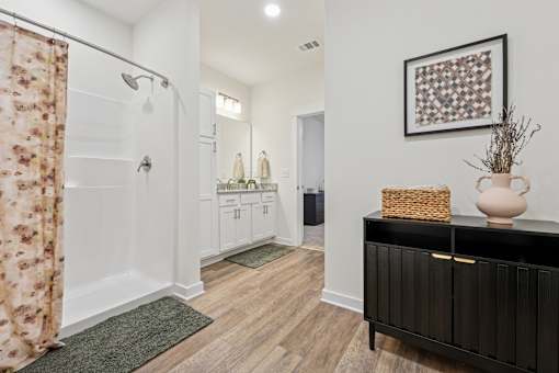 A bathroom with a floral shower curtain and a wooden floor.