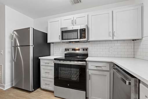 A modern kitchen with white cabinets and stainless steel appliances.