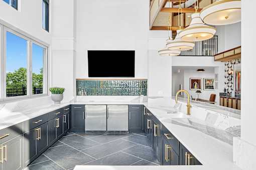 A modern kitchen with a large island and a flat screen TV mounted on the wall.
