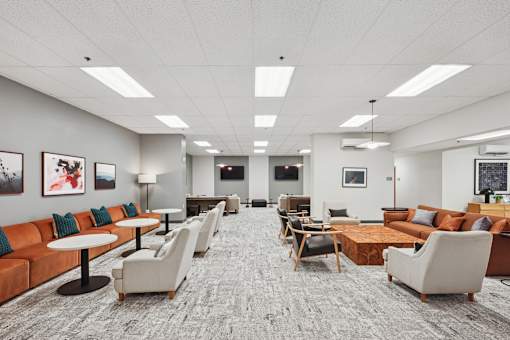 A spacious waiting area with orange couches and white chairs.