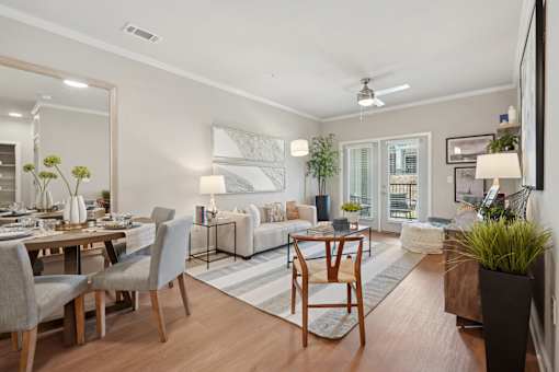 A well-lit, modern living room with a dining area and a kitchen in the background.
