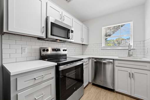 A kitchen with white cabinets and black appliances.