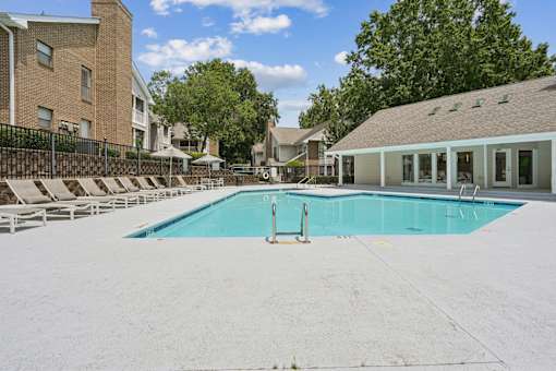 A swimming pool surrounded by a white fence and chairs.