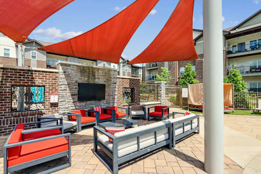 A patio with red and grey furniture and a red canopy.