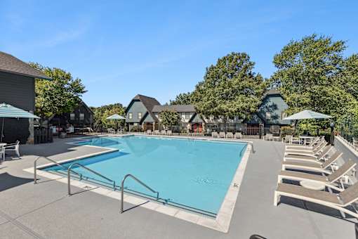 A large swimming pool surrounded by lounge chairs and umbrellas.