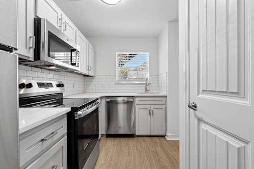A kitchen with white cabinets and black appliances.