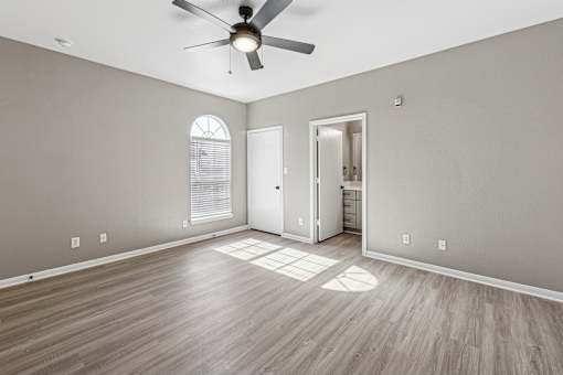 A room with a ceiling fan and wooden flooring.