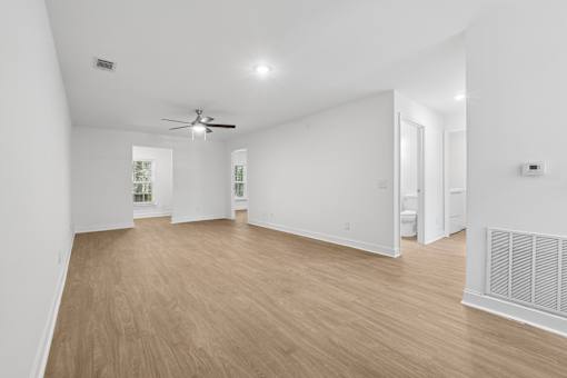 A spacious room with a ceiling fan and wooden flooring.