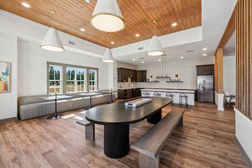 A modern kitchen with a wooden ceiling and a black table.