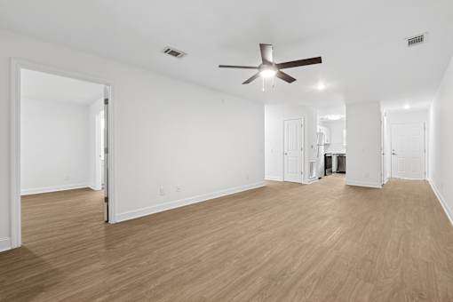 A room with a ceiling fan and wooden floors.
