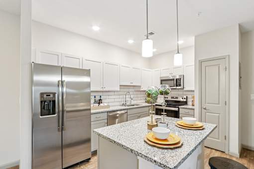 A modern kitchen with a granite countertop and stainless steel appliances.