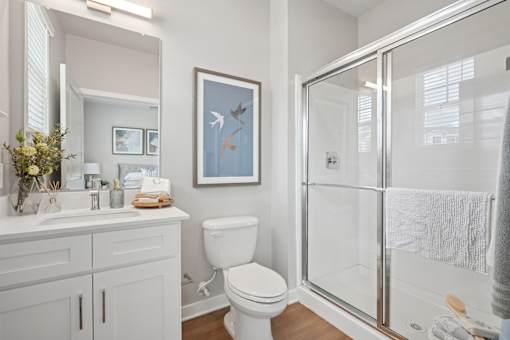 A white bathroom with a toilet, sink, and shower.