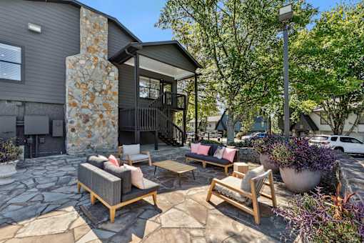A patio with a stone pillar and furniture.